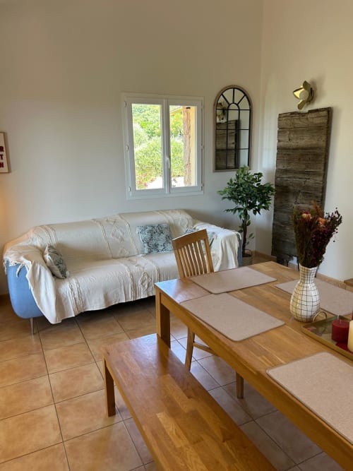 Lumineux séjour de Vista D'oro à Monacia d'Aullène avec canapé crème, table de salle à manger en bois et vue mer par portes blanches
