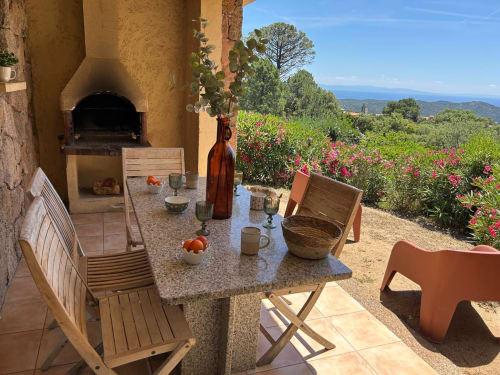 Terrasse avec table de repas, chaises en bois et four en pierre avec vue sur la mer à Vista D'oro, Monacia d'Aullène