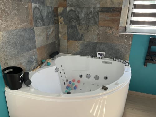Luxury corner jacuzzi bathtub with jets and colorful bath bombs in a modern bathroom at Mb Room 4 étoiles Love Room,