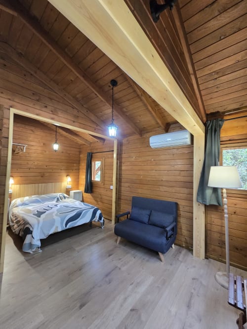 Dormitorio de cabaña de madera en Ecolodge de Cabañeros con cama, sofá y vista al jardín