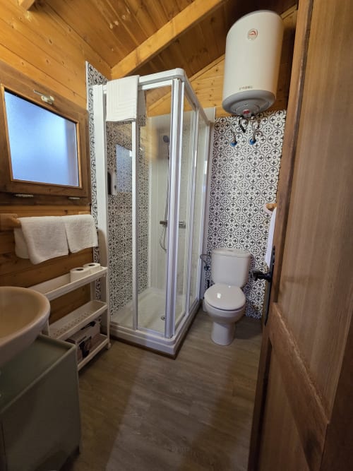 Baño del apartamento El Quejigo en el Ecolodge de Cabañeros con ducha, inodoro, lavabo y calentador de agua
