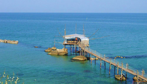 Wooden pier with beach house extending into turquoise Adriatic Sea at Pescara INN, Francavilla al Mare Italy