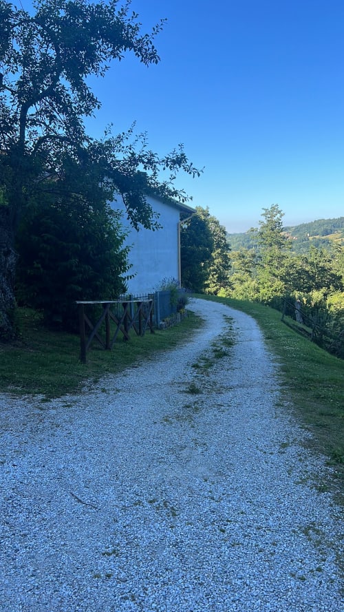Sentiero in ghiaia che conduce a villa blu circondata da alberi con vista sulle montagne presso R&B La Villa, San Benedetto Val di Sambro, Italia