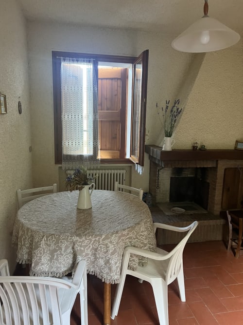 Sala da pranzo dell'appartamento La Casa nel Cammino Degli Dei con tavolo rotondo, camino e vista montagna presso R&B La Villa