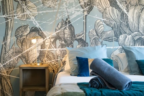 Chambre à La vie de château à Grignan avec papier peint botanique raffiné, lit aux oreillers bleus et lampe de chevet