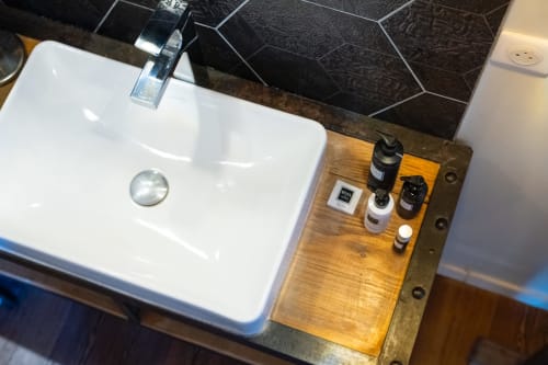 Lavabo moderne avec robinetterie chromée et étagère en bois garnie de produits de toilette à La vie de château, Grignan