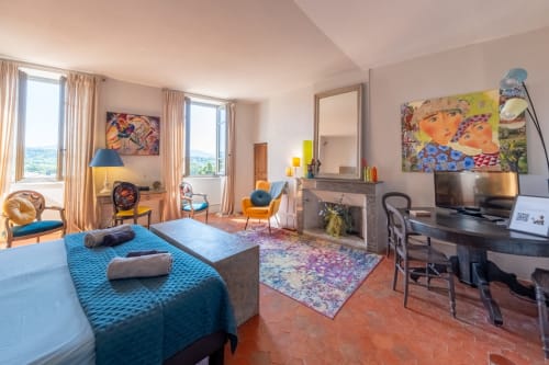 Spacieuse chambre familiale à La vie de château à Grignan avec vue sur les montagnes, literie bleue, cheminée et œuvres colorées