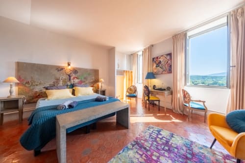 Chambre luxueuse à La Vie de Château Grignan avec vue sur les montagnes, literie bleue, tête de lit décorée et lumière naturelle