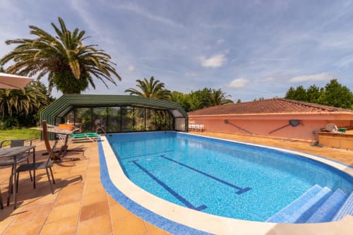 Piscina del Palacio Vasco con carriles de nado, palmeras y pabellón cubierto en Laukariz
