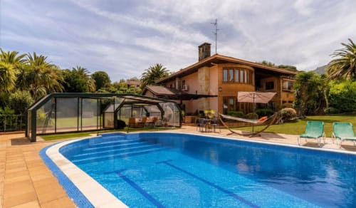 Piscina de la casa rural Basque Palace con tumbonas, zona de descanso cubierta y villa de terracota en Laukariz, España