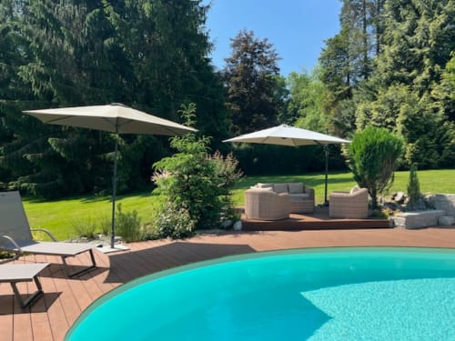 Espace piscine luxueux à La Bageatière avec transats, parasols et vue sur le jardin à Lépin-le-Lac