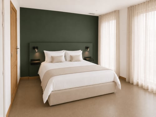 Chambre moderne du Gîte Le Palmier à Aigues-Mortes avec mur d'accent vert, literie blanche et lumière naturelle
