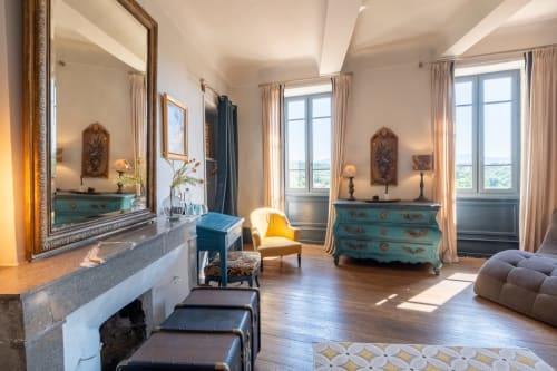 Chambre de luxe à La vie de château à Grignan avec commode turquoise, cheminée, vue sur les montagnes et mobilier élégant