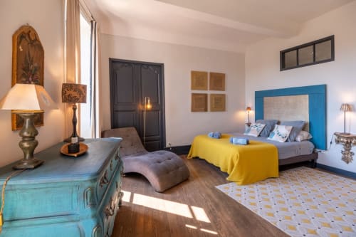 Chambre élégante à La vie de château à Grignan avec tête de lit bleue, parure jaune et vue sur les montagnes