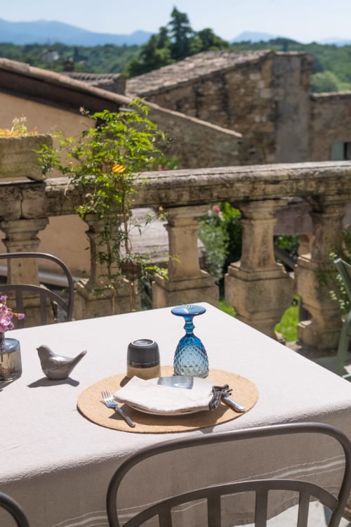 Élégante mise de table du Château hôtel de Grignan avec vue sur les ruines historiques et les vignobles