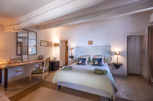 Chambre spacieuse à La vie de château à Grignan avec tête de lit bleue, bureau et poutres apparentes