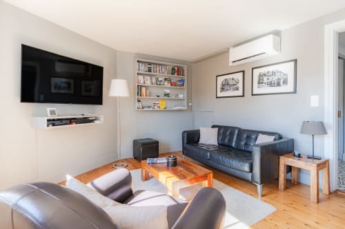 Modern living room at Les Maisons de Pierre et Valérie B&B in Honfleur with leather seating, wood table, and flat-screen TV