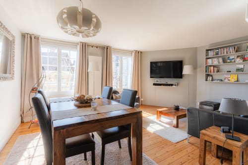 Spacious open-plan living area at Les Maisons de Pierre et Valérie in Honfleur with dining table, TV, bookshelves, and bright
