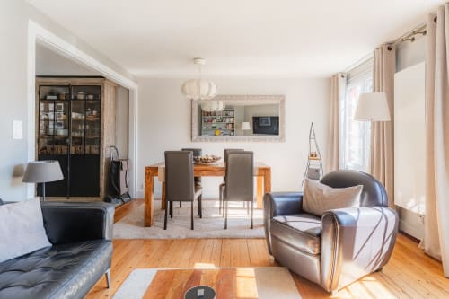 Modern living room in Honfleur B&B with leather armchair, wooden dining table, and bright windows overlooking the French