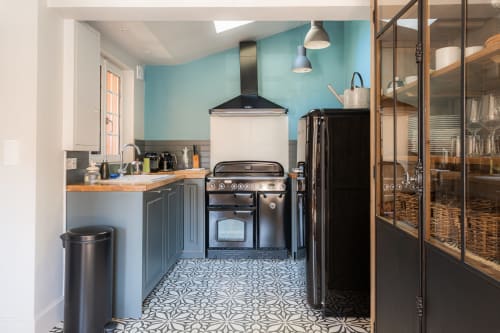 Modern kitchen at Les Maisons de Pierre et Valérie BnB in Honfleur with turquoise walls, black range cooker, and patterned