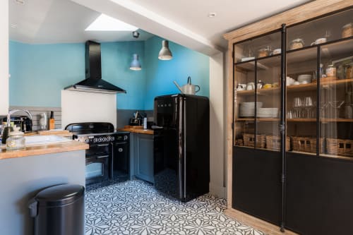 Modern kitchen at Les Maisons de Pierre et Valérie B&B in Honfleur with turquoise walls, black appliances, and patterned