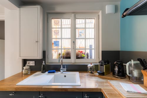 Modern kitchen at Les Maisons de Pierre et Valérie B&B in Honfleur with white sink, wooden counters, and garden view