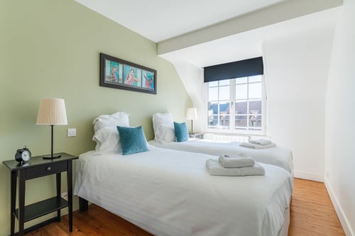 Bright guest bedroom at Les Maisons de Pierre et Valérie B&B in Honfleur with twin beds, sage walls, and bay windows