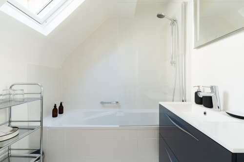 Modern bathroom with bathtub, dark vanity, and skylight at Les Maisons de Pierre et Valérie B&B in Honfleur