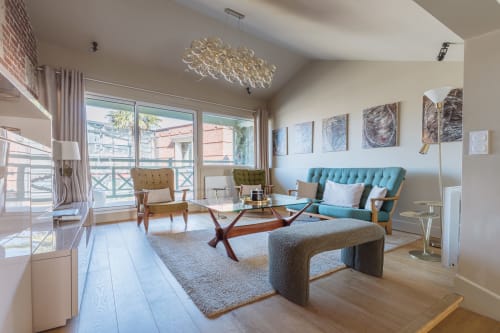 Modern Honfleur B&B living room with turquoise sofa, mid-century furniture, and balcony views