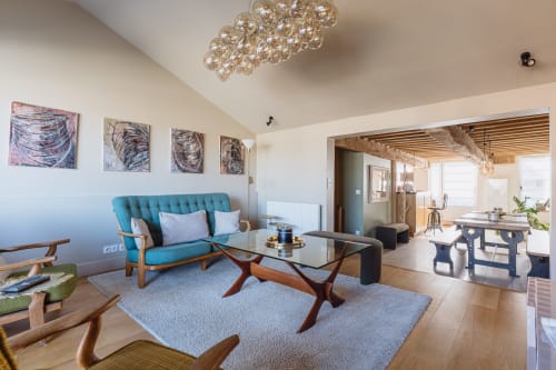 Modern living room at Les Maisons de Pierre et Valérie in Honfleur with turquoise sofa, glass table, and artwork