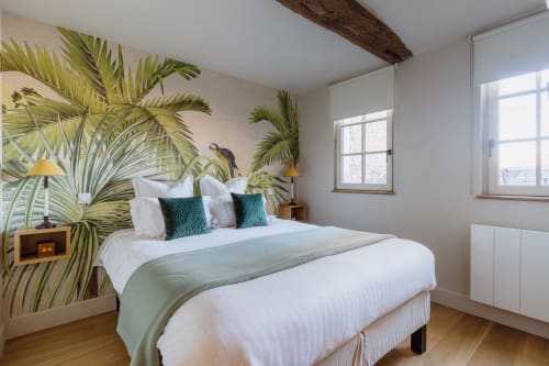 Tropical-themed bedroom at Les Maisons de Pierre et Valérie B&B in Honfleur with palm wallpaper and white bedding