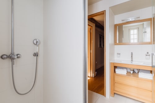 Modern bathroom at Les Maisons de Pierre et Valérie in Honfleur with wooden vanity, mirror, and shower fixtures.