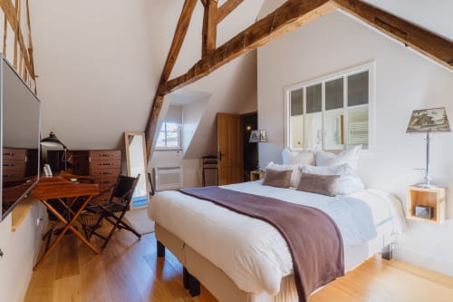 Spacious bedroom with exposed beams at Les Maisons de Pierre et Valérie, Honfleur. King bed, wooden desk, and French windows.