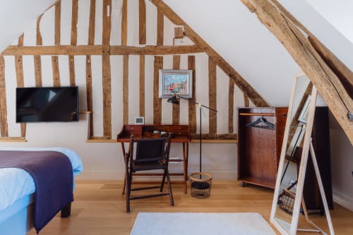 Rustic attic bedroom with exposed wooden beams, bed, TV, desk, and wooden furniture at Les Maisons de Pierre et Valérie in