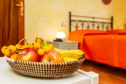 Woven fruit basket with apples and bananas on table in bright bedroom at Agriturismo Chiai Francesco, Bari Sardo