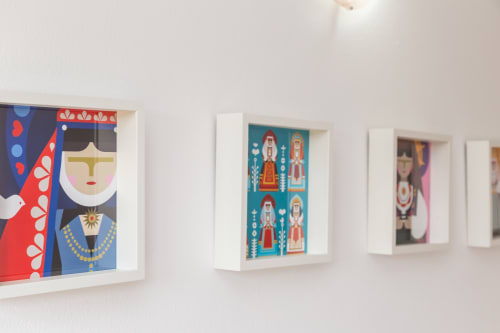 White framed artworks with colorful folk-inspired illustrations displayed on wall at Agriturismo Chiai Francesco apartment in