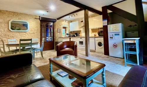 Séjour ouvert au Gîte La Vieille Ferme avec cuisine, salle à manger, salon et murs en pierre