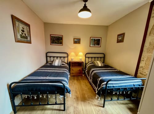 Chambre accueillante avec lits jumeaux au Gîte La Vieille Ferme à Saint-Geniès, parquets, literie en métal et éclairage chaleureux