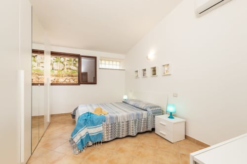 Bright bedroom with two beds, white nightstand, turquoise lamp, wooden floor, garden view windows at Agriturismo Chiai