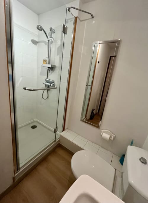 Salle de bain moderne avec douche vitrée, toilettes, lavabo et miroir au Gîte La Vieille Ferme, Saint-Geniès