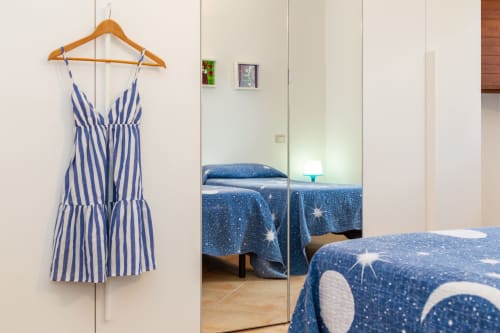 Blue striped dress on wooden hanger in bedroom with mirrored wardrobe and star-patterned bedding at Agriturismo Chiai