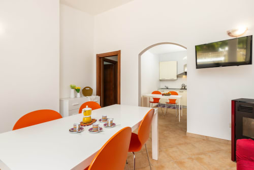 Modern dining area with orange chairs in apartment at Agriturismo Chiai Francesco, Bari Sardo, Italy