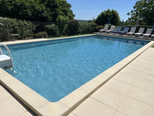 Piscine privée cristalline avec transats au Gîte La Vieille Ferme de La Doinie à Saint-Geniès, entourée d'un jardin luxuriant