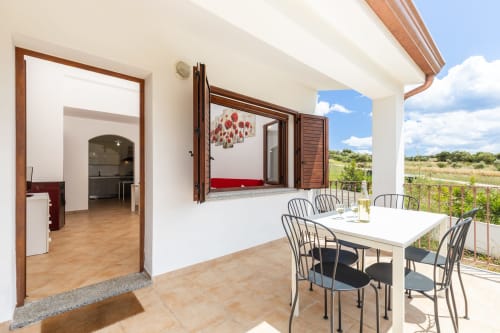 Sunny terrace of 3-bedroom apartment at Agriturismo Chiai Francesco, Bari Sardo, with dining table and garden views