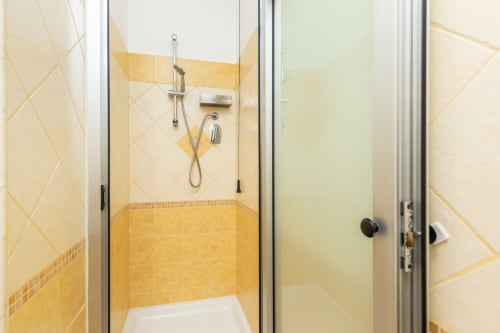 Modern bathroom with yellow tile and glass shower enclosure at Agriturismo Chiai Francesco, Bari Sardo
