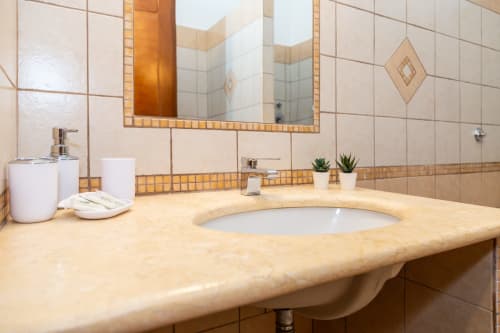 Modern bathroom vanity with marble countertop, round sink, and framed mirror at Agriturismo Chiai Francesco in Bari Sardo