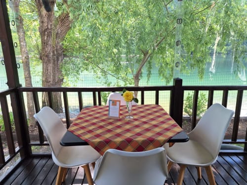 Allestimento ristorazione in riva al lago presso il Villaggio turistico Lago Dorato a Carlazzo con tavolo, sedie e fiore giallo con vista sull'acqua
