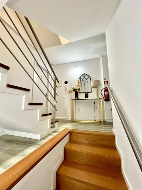Modern hostel hallway at Casa Augusta with wooden staircase, white walls, and contemporary furniture display in Braga,