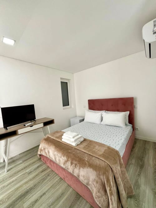 Modern Suite B bedroom at Casa Augusta hostel in Braga with red headboard, flat-screen TV, and air conditioning