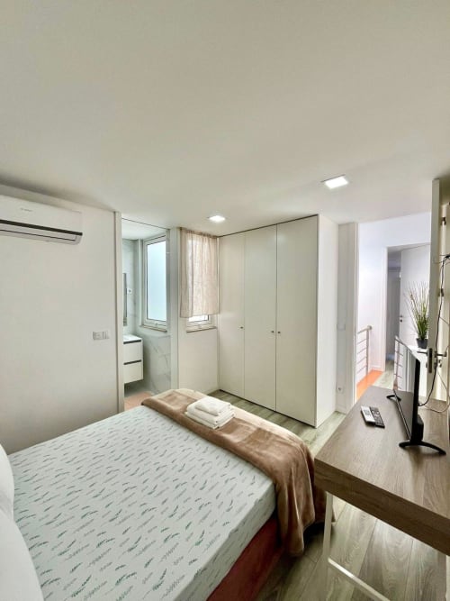 Modern bedroom suite at Casa Augusta hostel in Braga with bed, wardrobe, desk, ensuite bathroom, and air conditioning